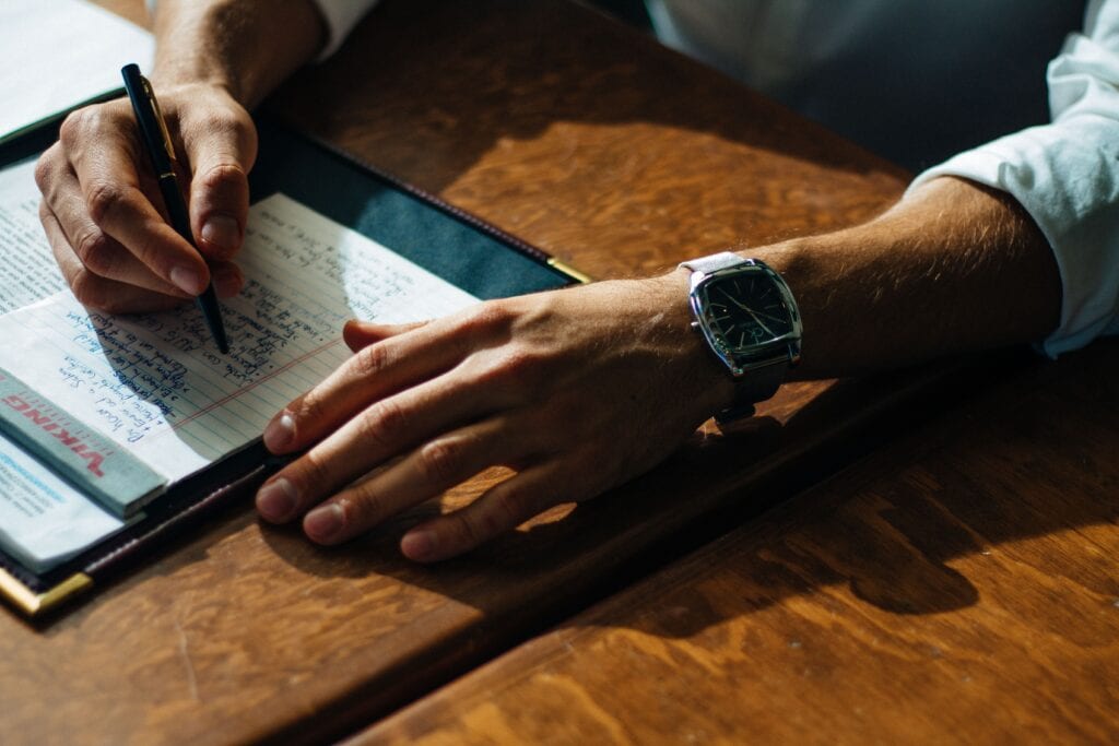 man writing down a list of bullet points on a piece of paper